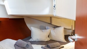 Una cama con almohadas y toallas, un cabecero de madera y una estructura blanca en el techo.