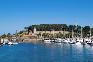 Un puerto deportivo con barcos amarrados, una estructura similar a un castillo y un edificio con techo rojo.