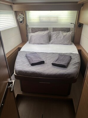 A compact bed with a headboard, two pillows, and two folded towels. - Sun-Kissed Sailing Adventure in the Ionian Islands, Lefkada (Lefkada)