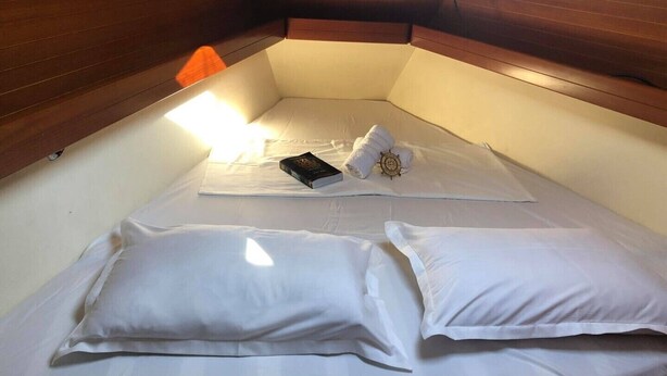 A small, cozy cabin with a wooden headboard, a single bed with white linens, a book, and a rolled towel. - Sun-Kissed Sailing Adventure in the Ionian Islands, Lefkada (Lefkada)