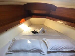 A small, cozy cabin with a wooden headboard, a single bed with white linens, a book, and a rolled towel. - Sun-Kissed Sailing Adventure in the Ionian Islands, Lefkada (Lefkada)
