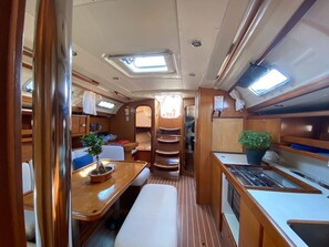 A compact interior with a dining area, kitchenette, and a small seating space. - Sun-Kissed Sailing Adventure in the Ionian Islands, Lefkada (Lefkada)