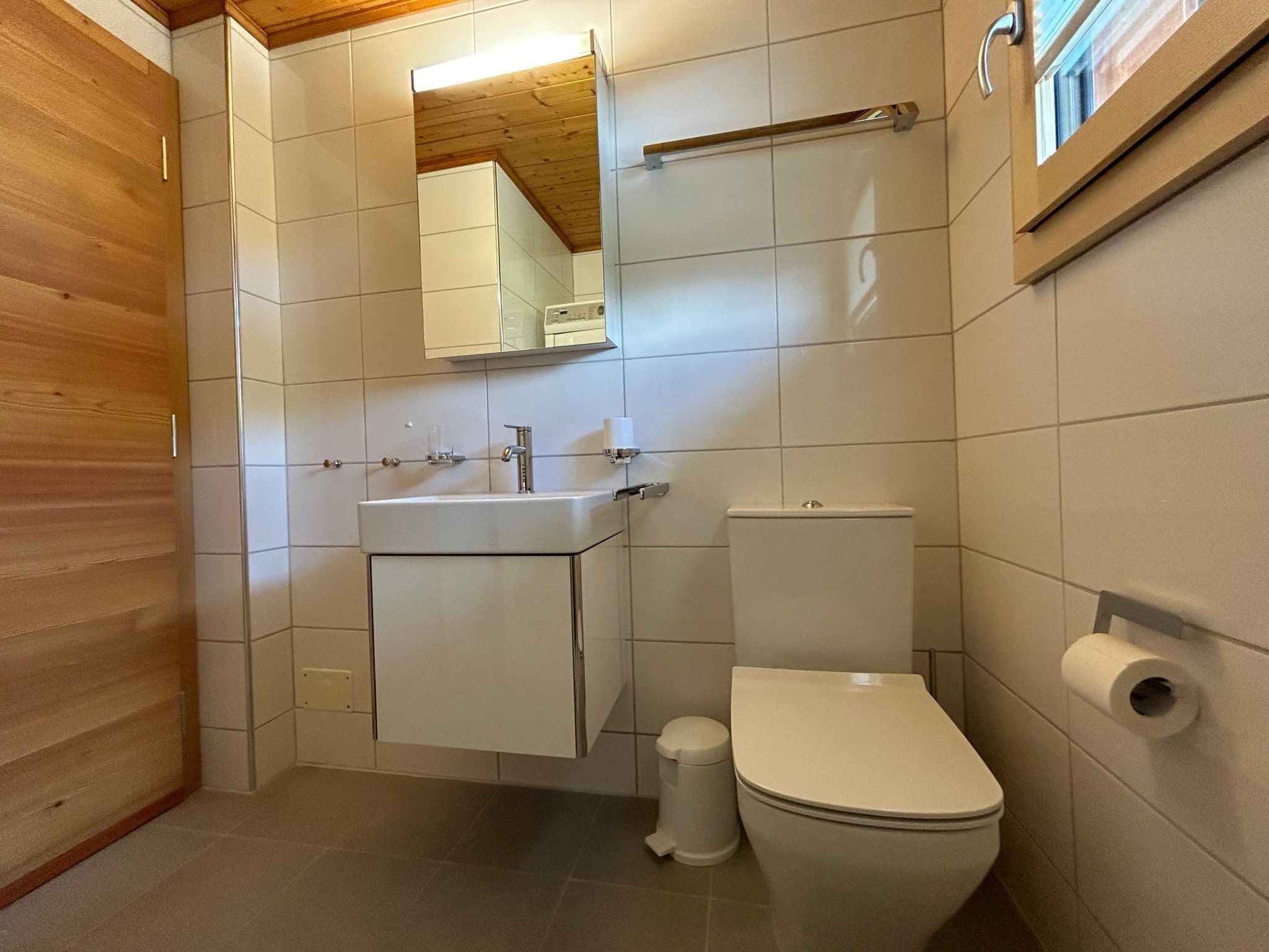 A bathroom with a toilet, sink, and mirror.