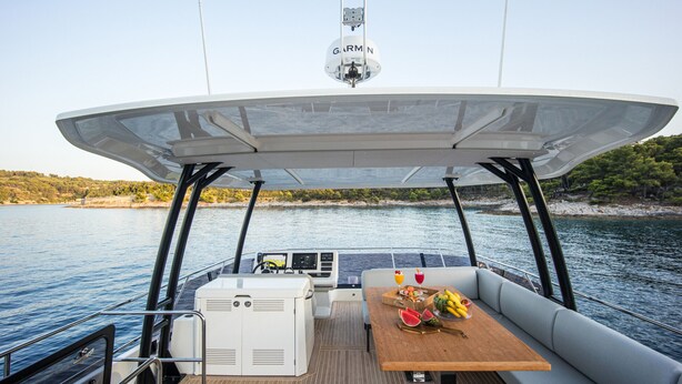 A boat deck with a table set for dining, a Garmin navigation device, and a view of the water and shoreline. - Sun-Kissed Sailing Adventure in Split, Croatia (Split)