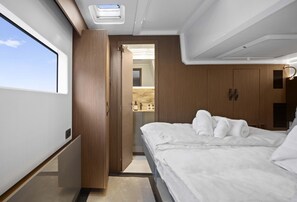 Ein Schlafzimmer mit Bett, Schrank, Badezimmer mit Pflegeartikeln und einem Fenster.