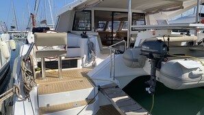 A boat deck with a Yamaha outboard motor, a cushioned seating area, and a small step leading to the water. - Sun-Kissed Sailing Adventure in Islas Sarónicas (Alimos)