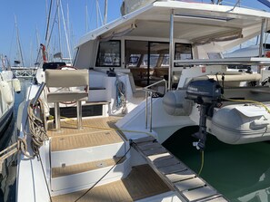 Ein Bootsdeck mit einem Yamaha Außenbordmotor, einer gepolsterten Sitzecke und einer kleinen Stufe zum Wasser.