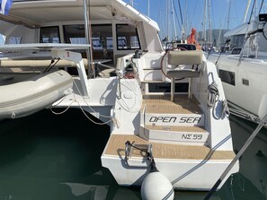 Un yacht portant l’inscription « En haute mer », avec un pont en bois et une cabine dotée de fenêtres.