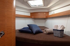 Ein gemütliches Blockhaus mit Dachfenster, einem Bett mit Kissen, einem aufgerollten Handtuch und einem gewebten Korb.