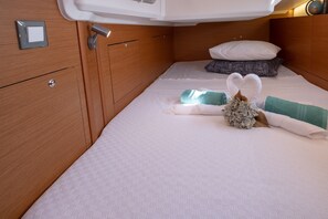 Ein ordentlich bezogenes Bett mit einem herzförmigen Kopfkissen und einer dekorativen Handtuchgestaltung.