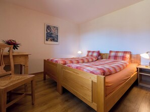 Ein Zimmer mit einem Einzelbett, einem Holzrahmen, einem Schreibtisch, einem Stuhl und einem Nachttisch mit Lampe.