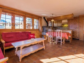 Ein gemütliches Zimmer mit einer roten Couch, einem Holzespeisetisch mit Stühlen und einer Küchenzeile mit Holdekor und Fliesenboden.