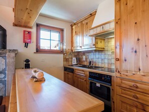 Eine Küche mit Holzausstattung, einem Herd, einem Wasserkocher und einem Fenster.