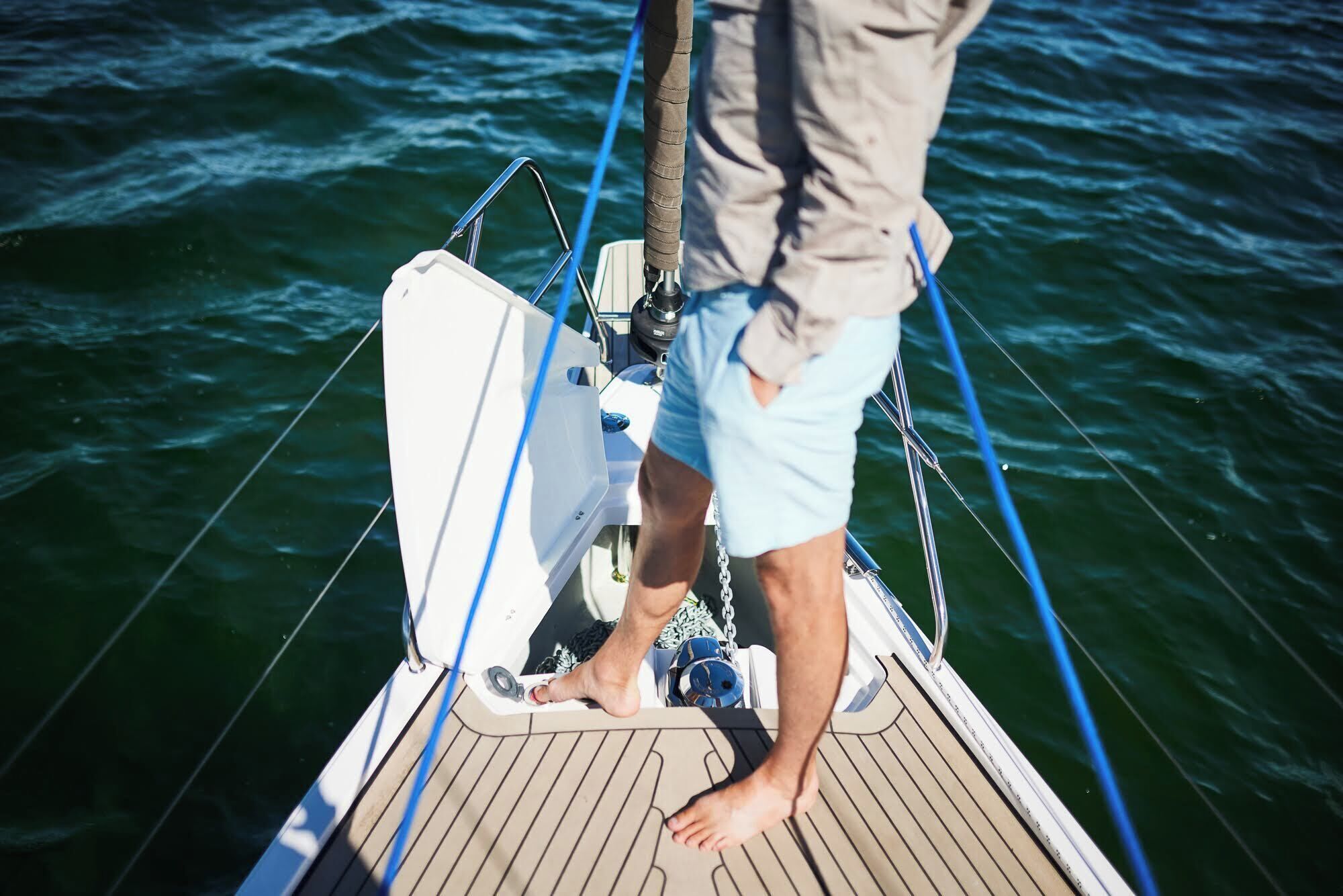 A person standing on a boat's deck, holding onto a rope.