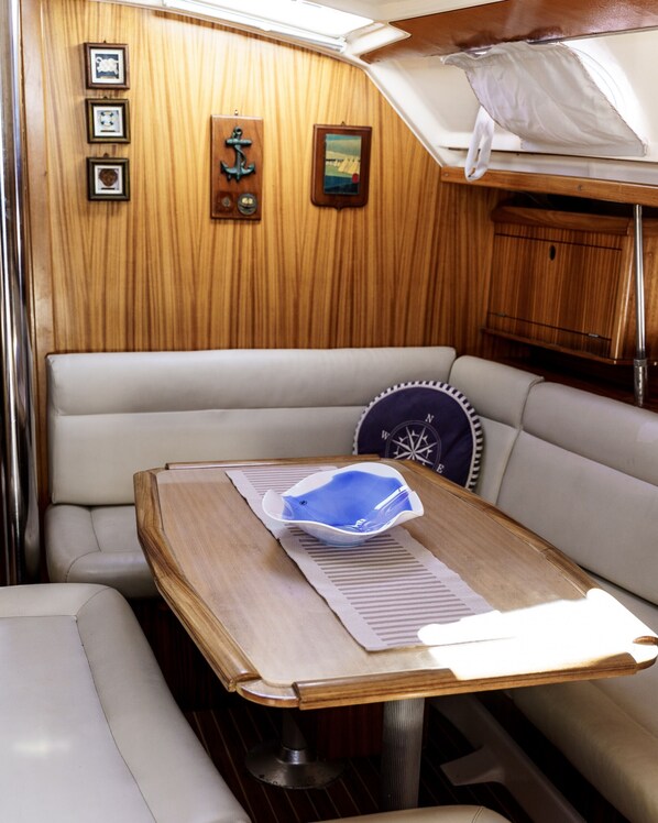 Une cabine de bateau avec un coin salon doté de sièges rembourrés, une table avec une carte et des panneaux en bois.