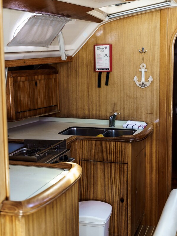 A compact galley with wooden cabinetry, a stainless steel sink, and a stove.