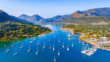 Un puerto deportivo con numerosos veleros amarrados, rodeado de colinas y montañas verdes y exuberantes.