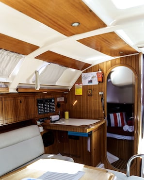 A compact RV interior with a kitchenette, a small seating area, and a sleeping berth.