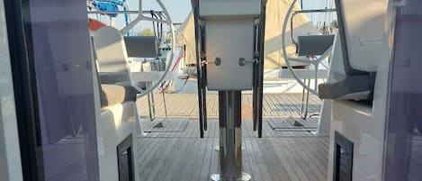Une terrasse avec une table centrale, deux chaises et une vue sur la mer et les autres bateaux.