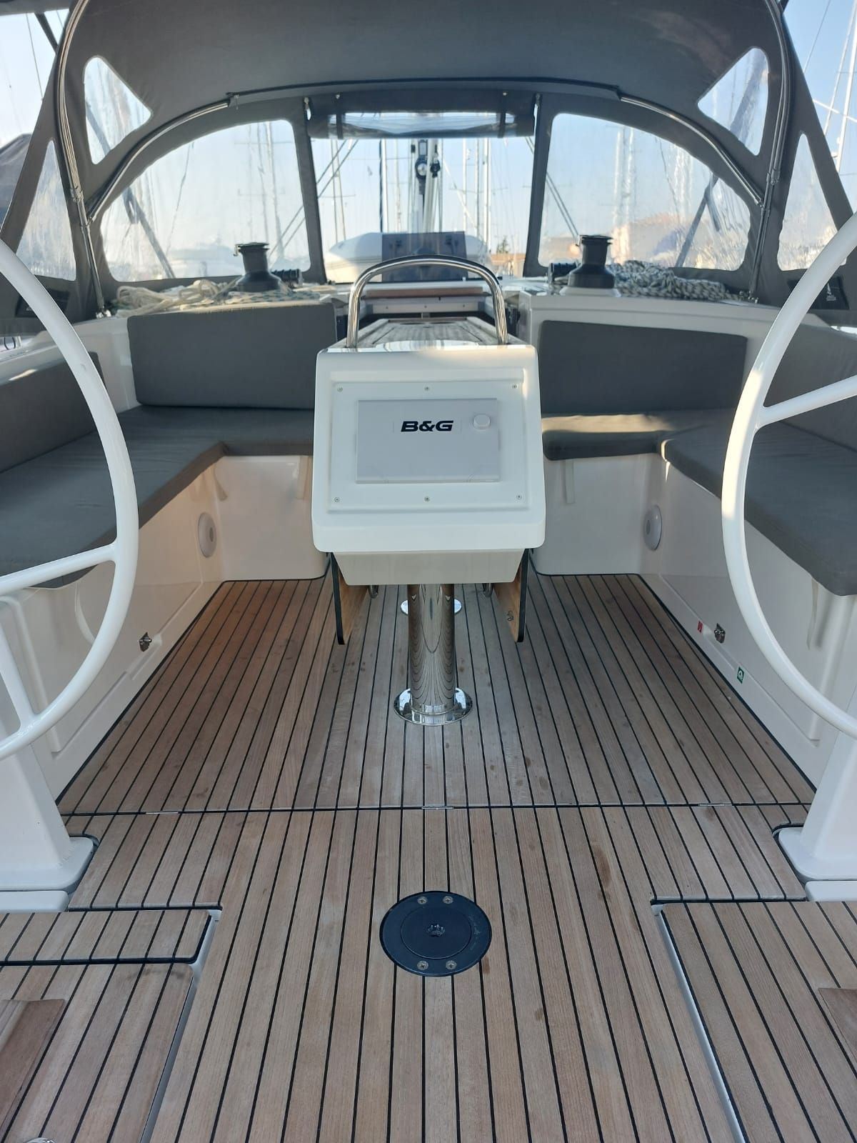 Ein Bootsdeck mit einer zentralen Konsole, Sitzbereichen und einem Holzboden.