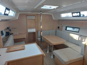 A compact interior with a dining area, seating, and a small kitchenette. - Sun-Kissed Sailing Adventure in the Ionian Islands, Lefkada (Lefkada)