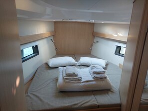 Quarto compacto e moderno, com cama, duas janelas e cabeceira de madeira.