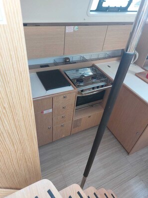 A compact kitchen with a stove, sink, and storage cabinets. - Sun-Kissed Sailing Adventure in the Ionian Islands, Lefkada (Lefkada)