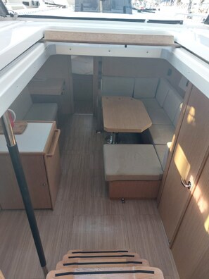 A compact boat interior with a seating area, storage compartments, and a small table. - Sun-Kissed Sailing Adventure in the Ionian Islands, Lefkada (Lefkada)