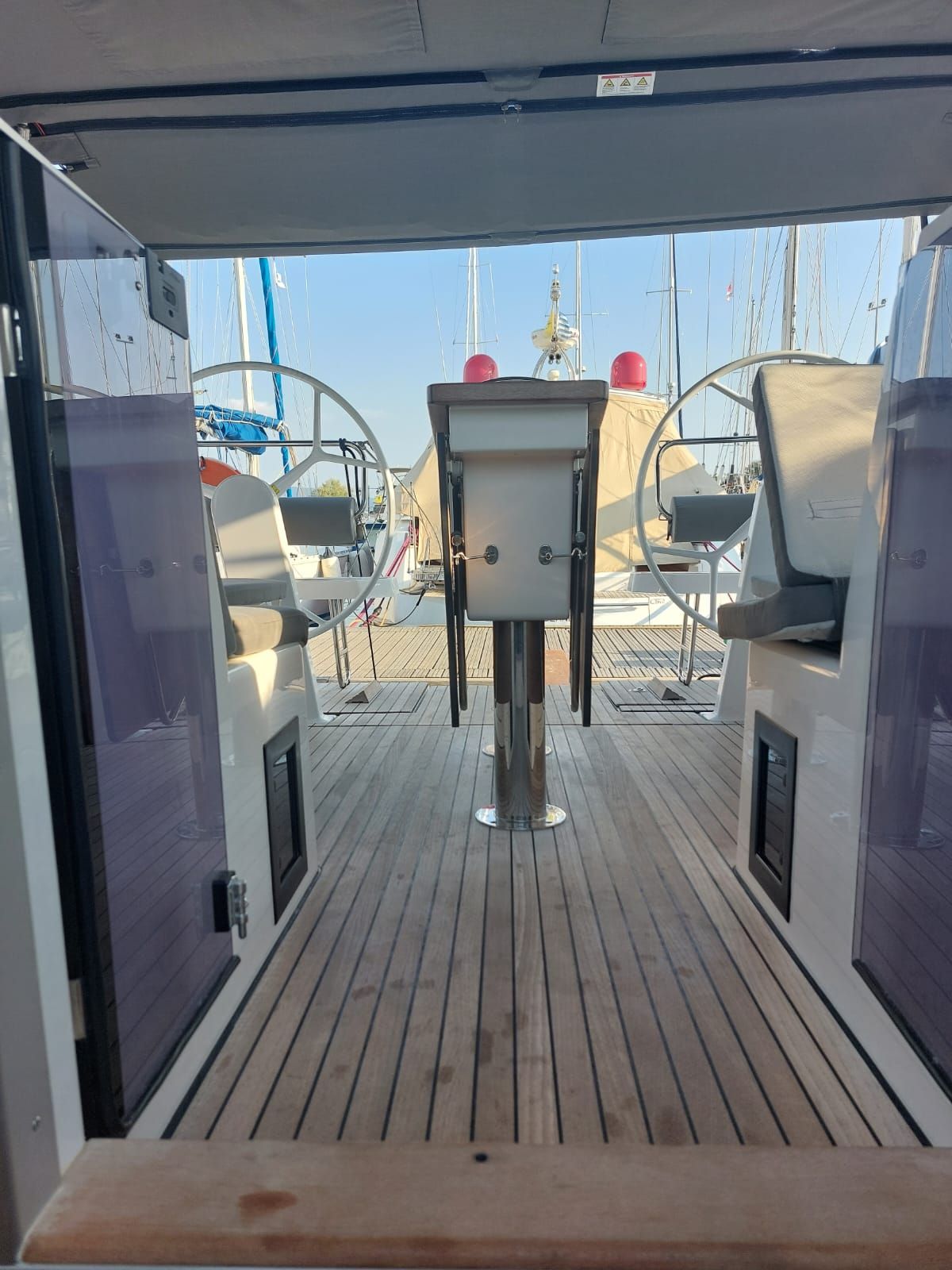 Eine Terrasse mit einem Tisch in der Mitte, zwei Stühlen und Blick auf das Meer und andere Boote.