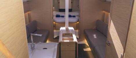 A compact interior with a bed, a small table, a sink, and a cabinet.