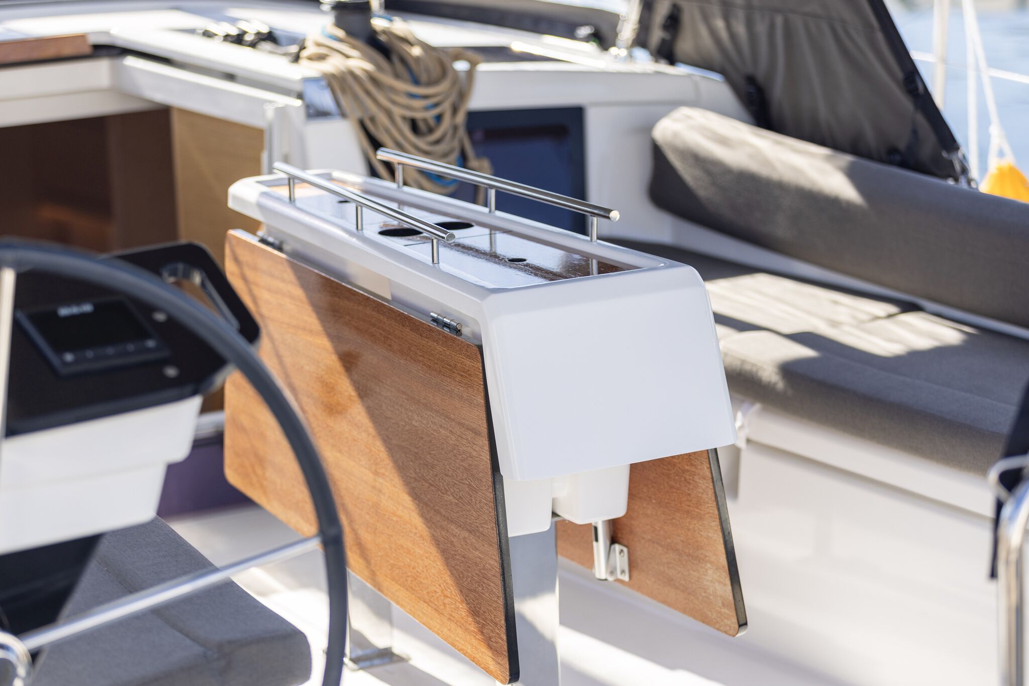 A boat's interior with a control panel, wooden paneling, and a cushioned seating area.