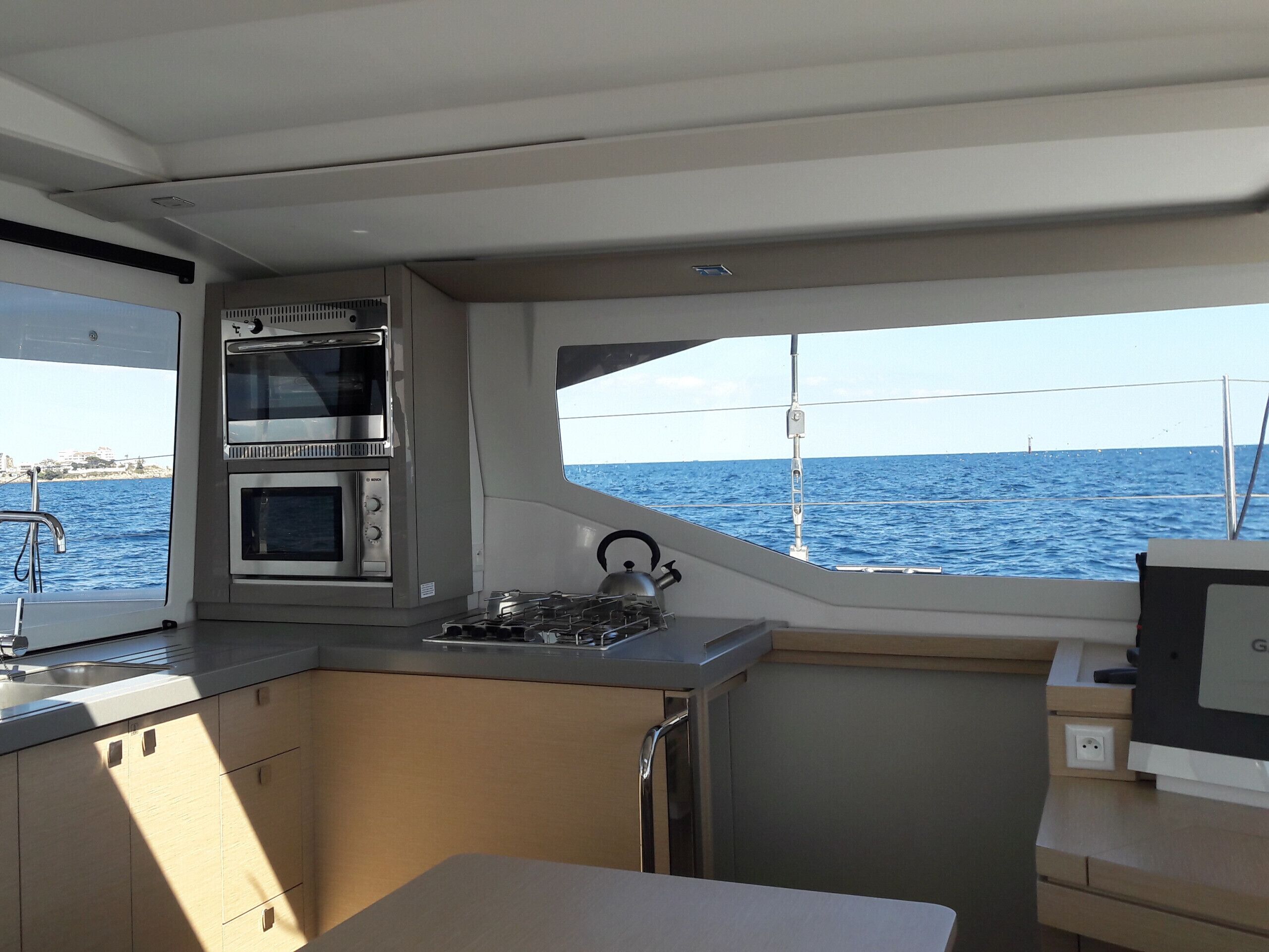 Une petite cuisine fonctionnelle équipée d’une cuisinière, d’un four et d’un évier, donnant sur une mer calme.