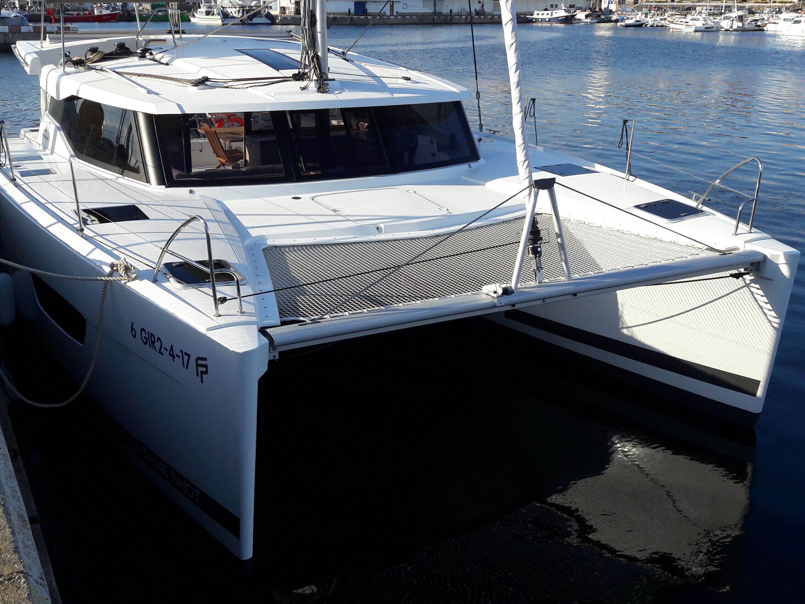 A white yacht docked at a marina with a covered deck area.