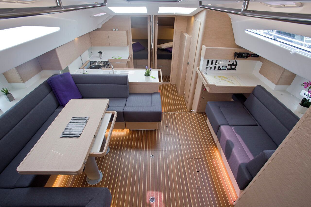 A compact interior with a dining area, seating, a kitchenette, and a small bathroom.