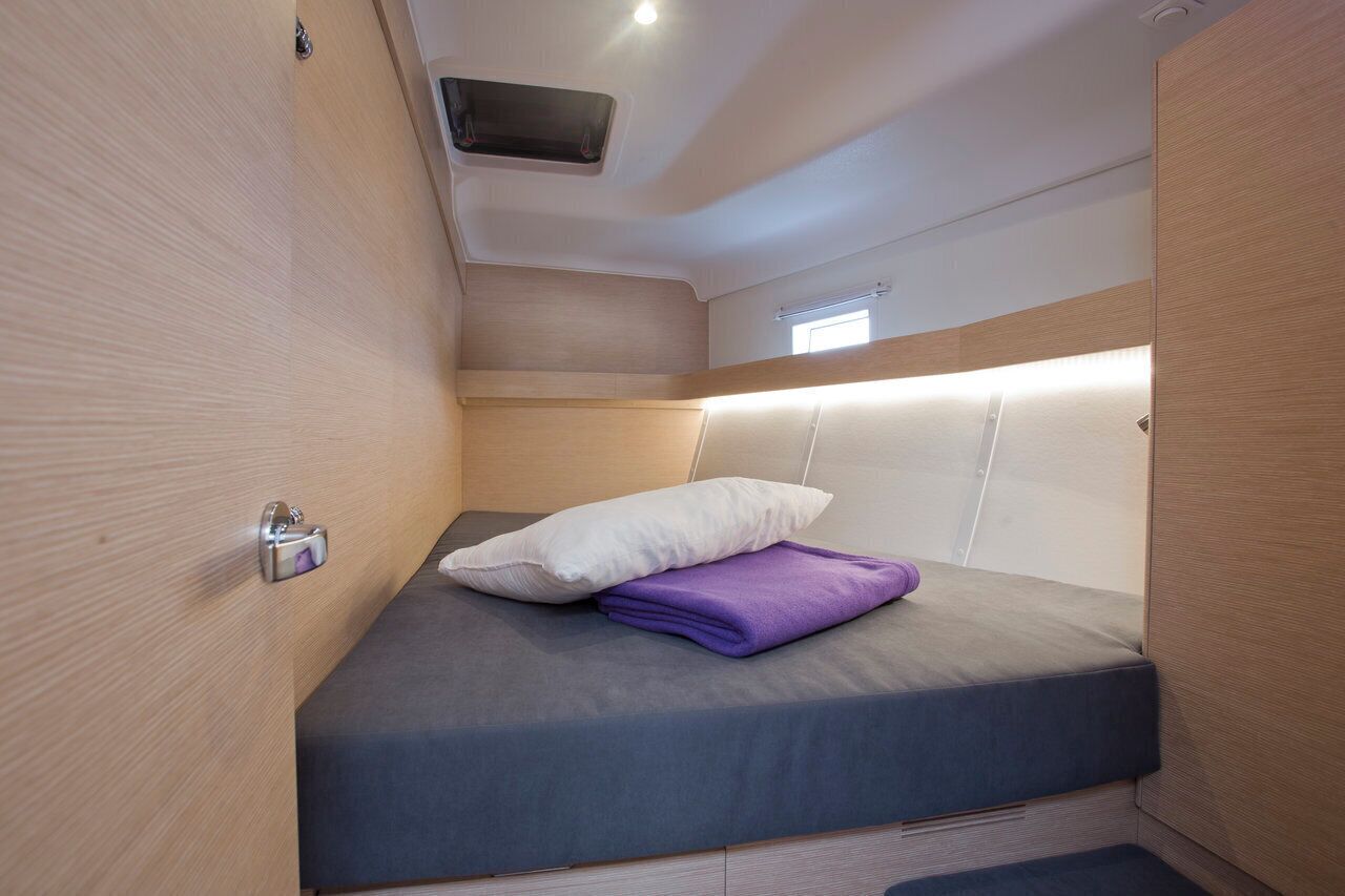Una cabaña pequeña y luminosa, con una cama individual, un ventanal y una rejilla en el techo.