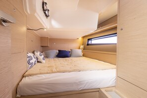 Ein kompakter, gut beleuchteter Innenraum mit einem Bett, Stauraumschränken und einem Fenster für natürliches Licht.