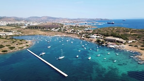 An aerial view of a coastal town with a marina filled with boats, a pier, and surrounding buildings.