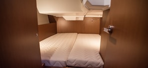 Ein schmaliges Bett mit einer strukturierten Matratze, einem Kopfteil und einer Tür mit Griff.