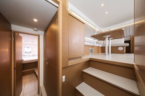 A compact, modern interior with wooden finishes, built-in storage, and a small seating area. - Sibenik Sun-soaked Sailing: A Luxurious Croatian Voyage (Pirovac)