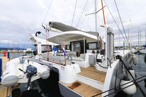 Un velero amarrado en un puerto deportivo, con una cubierta protegida, un timón y un motor fueraborda Yamaha.