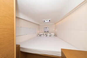 Habitación pequeña con cama individual, una ventana y proyector en el techo.