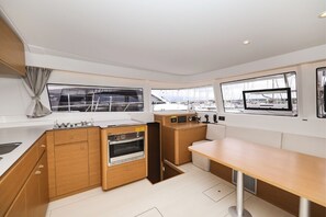A modern kitchen with wooden cabinets, a built-in oven, and a large window overlooking a marina. - Sibenik Sun-soaked Sailing: A Luxurious Croatian Voyage (Pirovac)