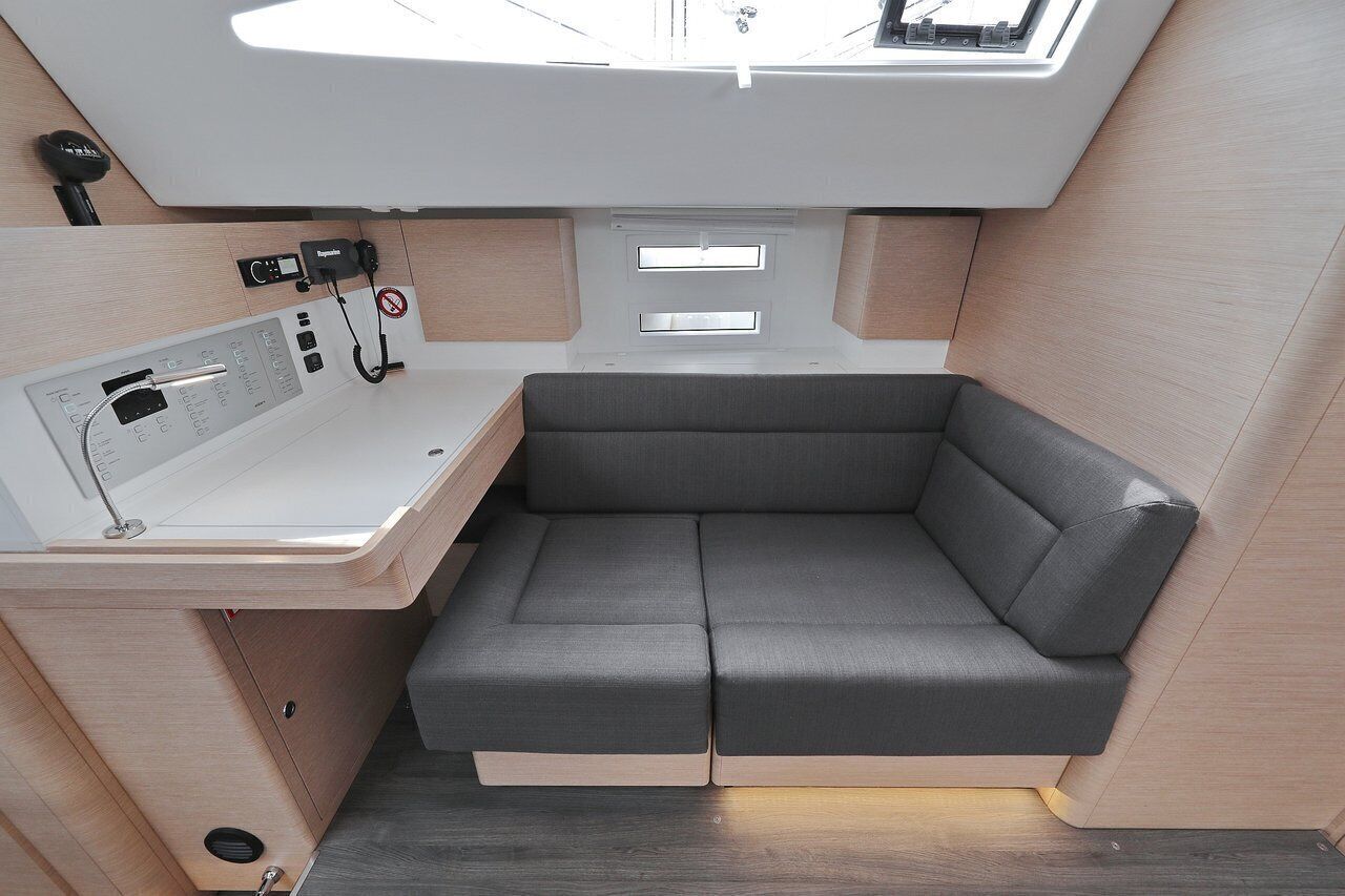 A compact interior with a cushioned seating area, a control panel, and a window.