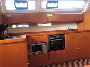 Cozinha compacta com micro-ondas, forno e máquina de café.