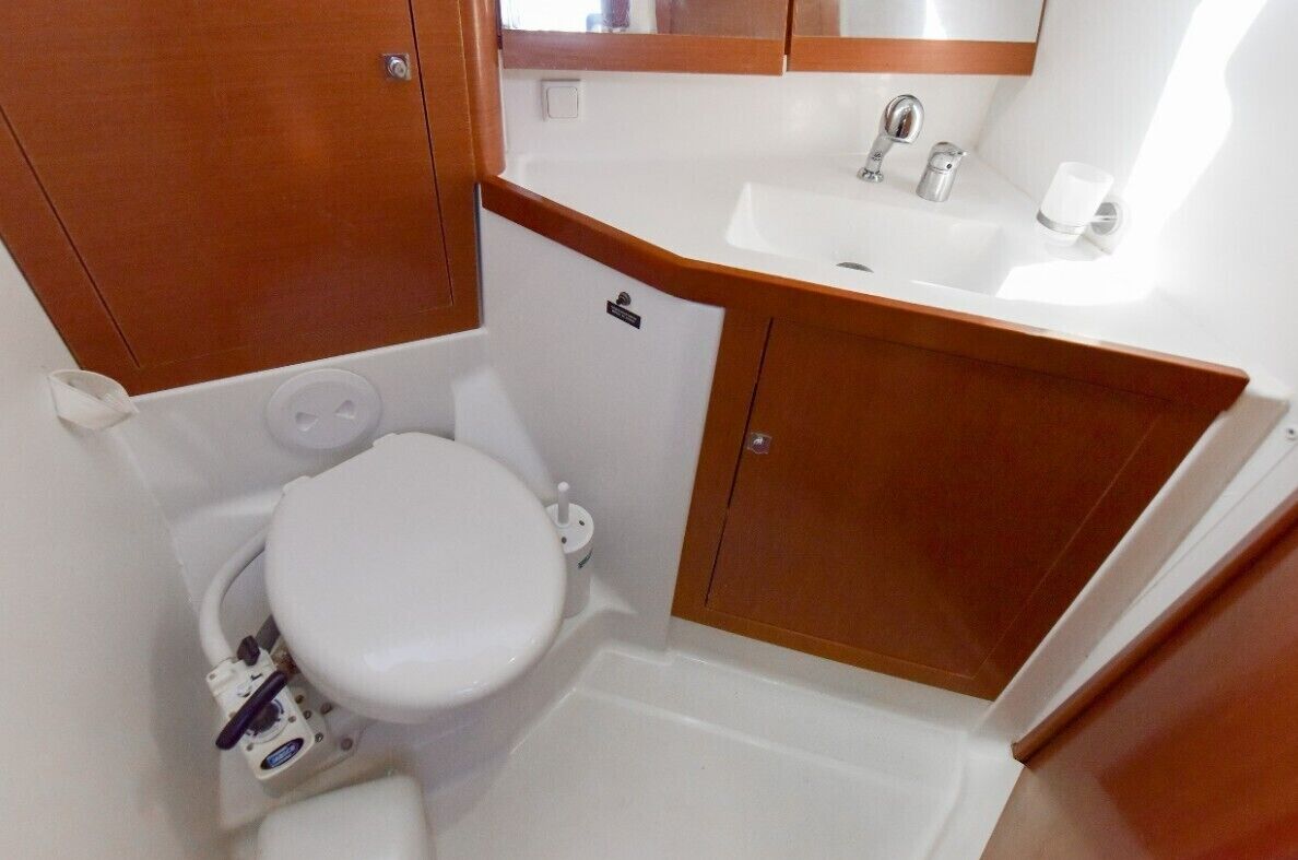 A compact bathroom with a white toilet, a sink, and wooden cabinets.