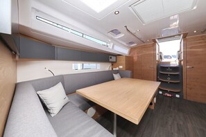 A compact RV interior with a dining table, seating area, and storage cabinets. - Sun-Kissed Sailing Adventure in Zadar, Croatia (Biograd na moru)