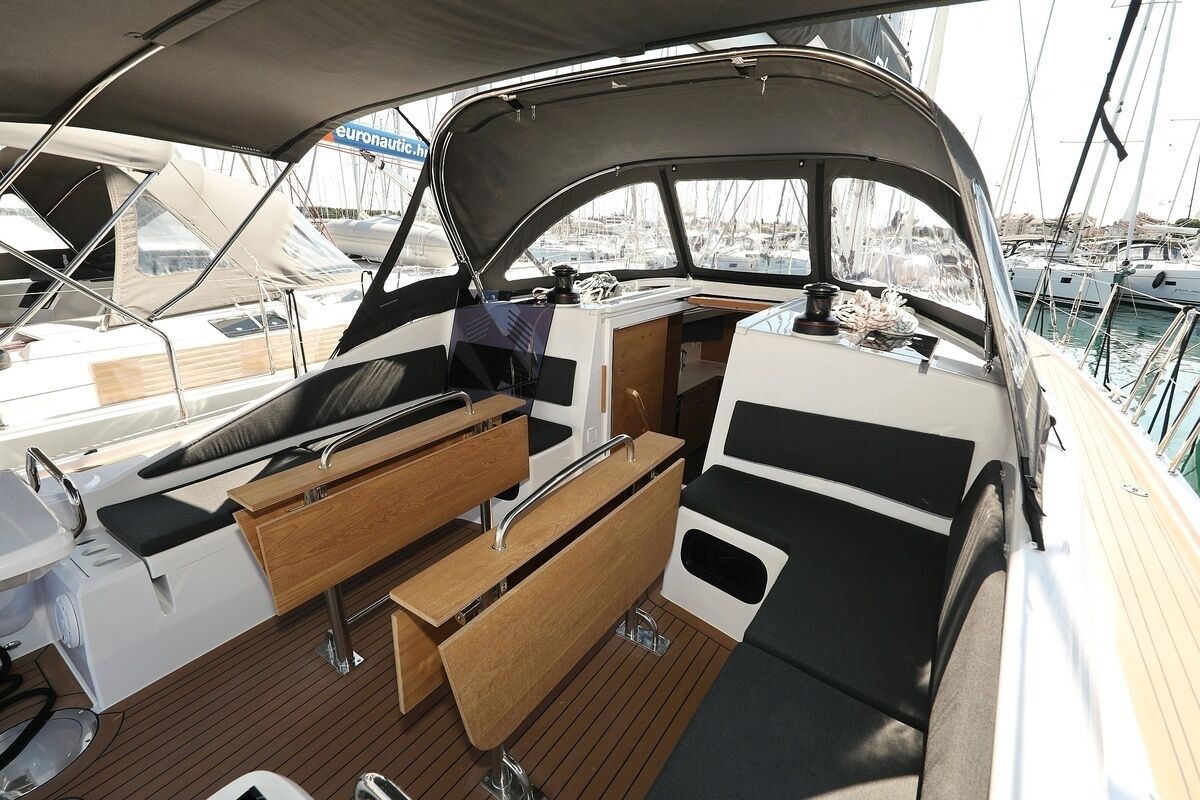 A boat deck with a seating area, a table, and a view of other boats.