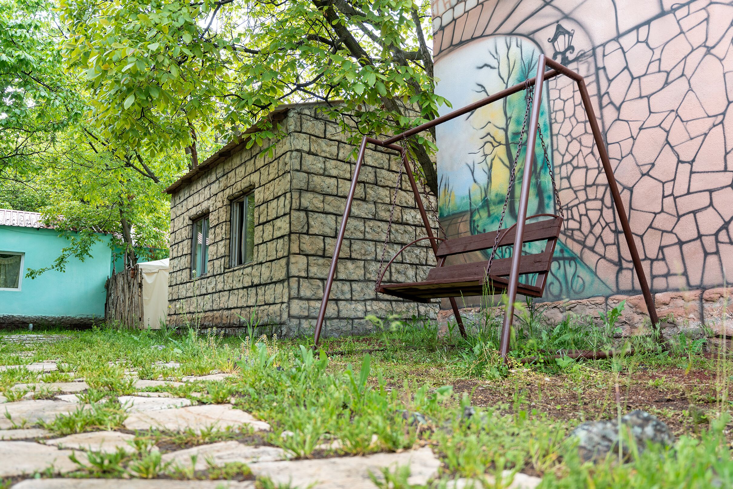 Un bâtiment en pierre avec une fenêtre, une balançoire et une fresque murale.