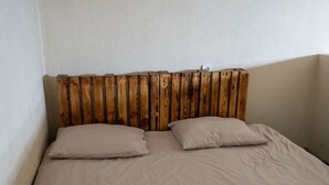 Un lit avec une tête de lit en bois, deux oreillers et un mur uni.