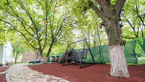 Un parc avec un sentier en pierre, une balançoire et un arbre.